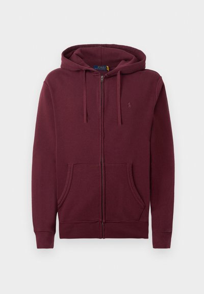 Sweatshirt zip-up em bordeaux com capuz ajustável, bolsos frontais e logo bordado discreto no peito, em contraste com um fundo branco.