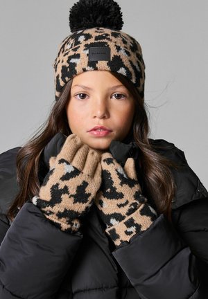 Pletená čiapka s leopardím vzorom a čiernym pom-pomom, spolu s vyhovujúcimi rukavicami. Farby obsahujú pieskovú, čiernu a sivú. Mäkkučká textura, priliehajúci strih.