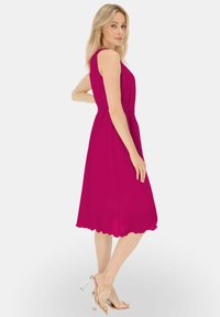 Fuksjowa sukienka bez rękawów z dopasowaną talią i rozkloszowanym dołem, z falbaniastym wykończeniem. W zestawie przezroczyste sandały na obcasie.