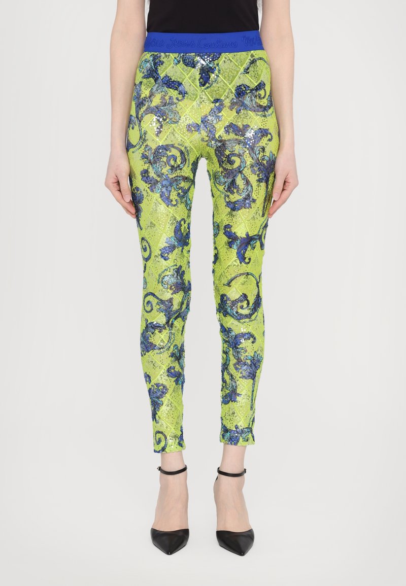 Leggings verdes con lentejuelas que presentan una cinturilla azul, adornados con un intrincado patrón floral azul. Diseño ajustado con pierna entallada.