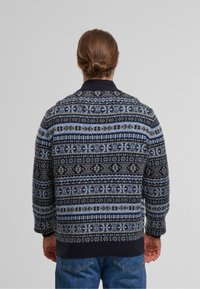 Strickpullover in Marineblau und Hellblau mit geometrischen Mustern. Rippenkragen und -bündchen, bequemer Schnitt und strukturierter Stoffdesign.