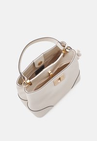 Ljust grå handväska med en texturerad yta, guldfärgad beslag och en strukturerad form. Har ett handtag och ett lås.