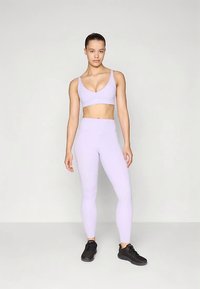 Lilaka spordirinnahoidja ja retuusid venivast materjalist, millel on kehakuju järgnev disain, sile pind ja nähtamatud mustrid.