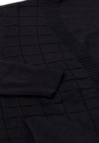 Maglione nero con un motivo a griglia testurizzato, colletto e polsini a coste. Tessuto morbido con una vestibilità comoda.
