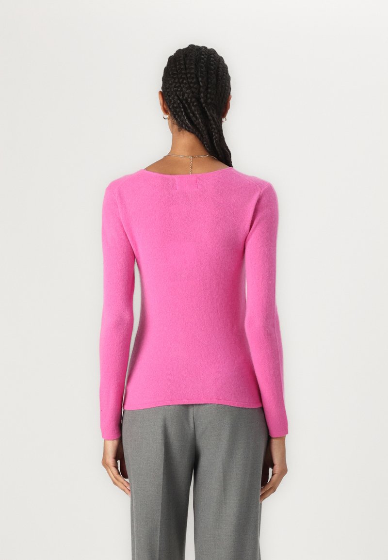 Figurbetonter, langärmeliger Pullover in leuchtendem Pink aus strukturiertem Strickmaterial. Mit einem runden Ausschnitt und einem verlängerten Rücken mit dezenten Nahtdetails.