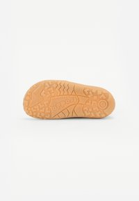 Semelle de chaussure en caoutchouc avec une surface texturée de couleur brun clair. Présente des crampons marquants et le nom de la marque "Froddo" moulé au centre.