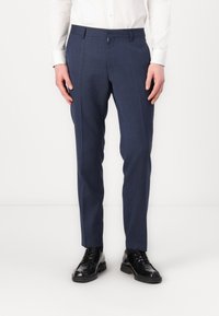 Navy blue tailored trousers with a subtle check pattern, slim fit design, and front pockets, paired with black dress shoes.