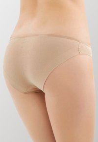 Boxer in tessuto beige morbido e elasticizzato, dallo stile hipster. Presenta una finitura liscia, una vita elasticizzata, cuciture semplici e senza decorazioni.