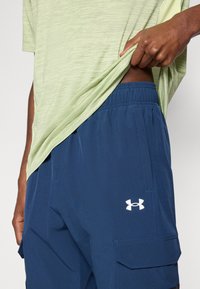 Ανοιχτό πράσινο T-shirt με υφή, συνδυασμένο με σκούρα μπλε σορτς που διαθέτουν πλαϊνές τσέπες και λευκό λογότυπο στο αριστερό μηρό.