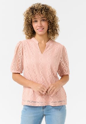 Lyserød bluse med geometrisk blonde-design, korte puffærmer og V-udskæring. Stoffet har en delikat tekstur og åben arbejde detaljer.