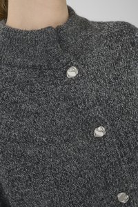Grauer Strickpullover mit hohem Kragen, strukturiertem Stoff und zwei runden silbernen Knöpfen als Akzentdetails.