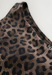 Tissu en imprimé léopard présentant des taches marron foncé et noires sur fond marron clair, avec une texture lisse et un col rond.