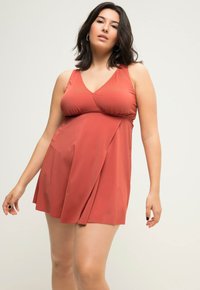 Abito da nuoto rosso in tessuto morbido e leggero. Presenta una scollatura a V, design senza maniche e una parte inferiore a gonna con pieghe.