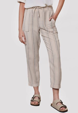 Lichtbeige gestreepte broek met een trekkoord in de taille, zijzakken en een relaxte pasvorm, gecombineerd met neutrale slidesandalen.