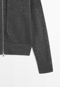 Dark gray knitted cardigan featuring a zip closure, ribbed cuffs, and hem, with a soft texture and a relaxed design.