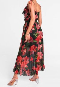 Blomster maxi kjole med flæsebeklædte stropper, med en sort bund og store røde blomster, afsluttet med en præget kant og klare hælede sandaler.