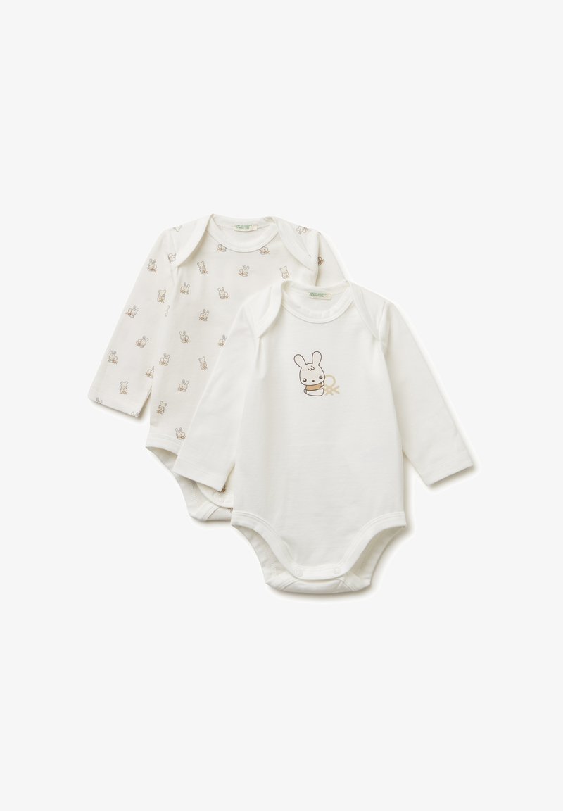 Dvě dlouhé rukávy dětských bodýček z měkké bílé bavlny. Jedno má malý vzor králíčka; druhé má design králíčka s jemnými hnědými akcenty.