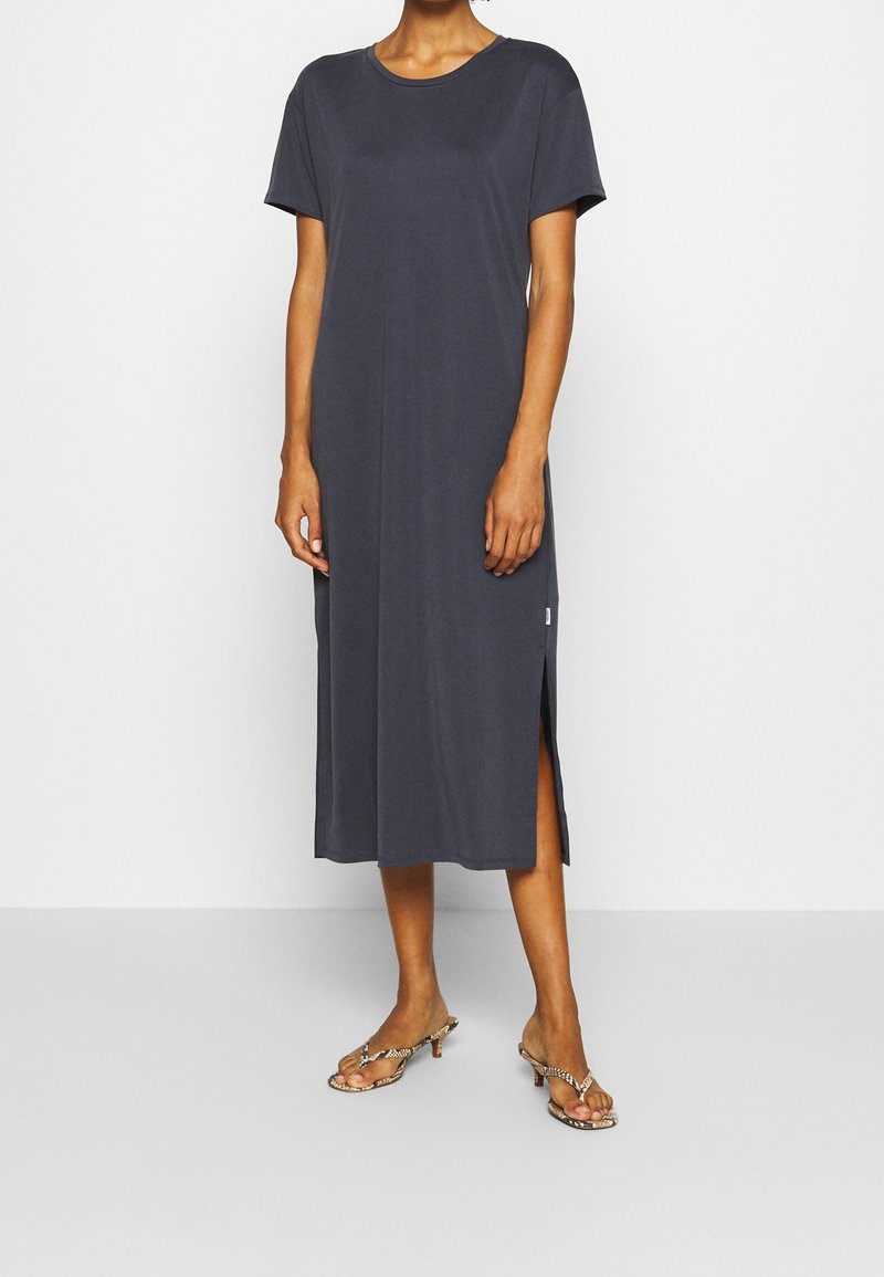 Abito midi grigio scuro con maniche corte, scollatura rotonda, spacchi laterali e morbida texture. Indossato con sandali stampa animale.