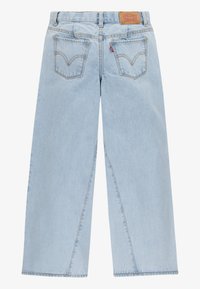 Jeans ampi di colore blu chiaro in denim, con vita alta, tasche posteriori con firma e un'etichetta in pelle marrone con il marchio in vita.