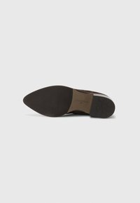 Botte chelsea en daim marron avec un bout pointu, semelle en caoutchouc et un talon robuste. Présente une semelle intérieure marquée et une couture supérieure lisse.