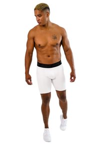 Boxer briefs bianchi con una vita nera etichettata "STARK SOUL." Il modello ha un fisico tonico e indossa scarpe da ginnastica chiare. Texture liscia.