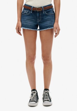 Denim shorts in dark blue with frayed hems, paired with a woven brown belt. Worn with black high-top sneakers.