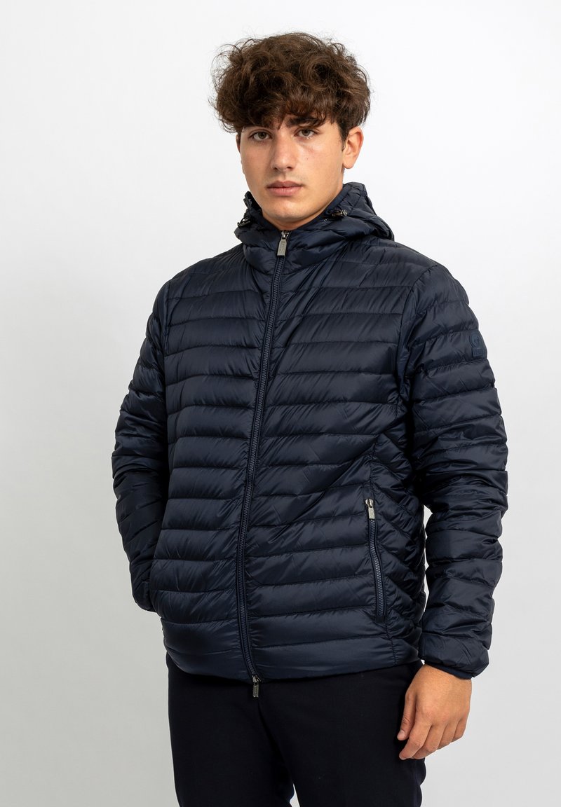 Giacca a vento navy con design trapuntato testurizzato, chiusura a zip completa e cappuccio attaccato. Caratterizzata da tasche laterali con zip e polsini elasticizzati.