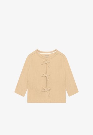 Beige top met lange mouwen, gemaakt van gestructureerde stof en met drie strikaccenten aan de voorkant, voorzien van een ronde halslijn en drukknoopsluiting.