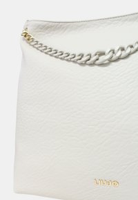 Borsa a spalla in pelle bianca con una finitura testurizzata, dotata di tracolla in catena argento e logo del marchio dorato. Design liscio e semplice.