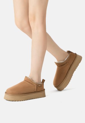 Brown slip-on shoes with a soft, fleece lining, rubber soles, and thick platform; smooth texture and rounded toe design.