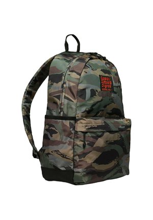 Sac à dos camouflé en tissu durable, avec des bretelles rembourrées, une poche frontale et un patch logo orange. Forme arrondie avec des accents sombres.
