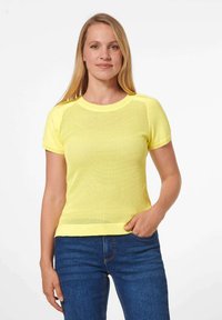 Geel gebreid shirt met korte mouwen en een textuurpatroon, ronde hals en ribbelaccenten. Gecombineerd met blauwe jeans. Eenvoudig en ademend ontwerp.