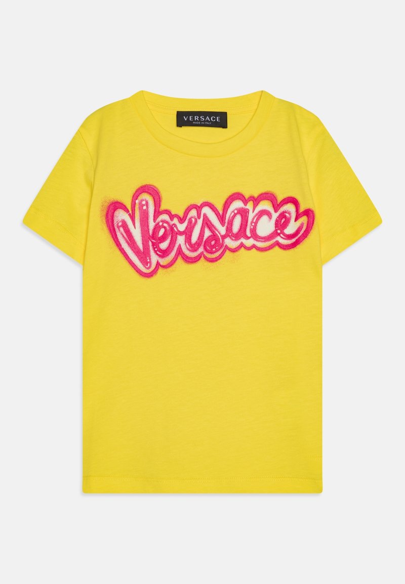 Gul bomulds T-shirt med en fremtrædende pink logo tekst "Versace" i en legesyg, buet skrifttype. Korte ærmer og rund halsudskæring.