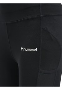 Svarta atletiska leggings i mjuk och stretchig tyg, med en sidoficka, platta sömmar och en vit "hummel"-logotyp på låret.