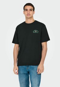 Zwarte katoenen T-shirt met een groen logo waarop "BEIGEL LANE 24/7 SHOREDITCH" op de borst staat. Korte mouwen en een ontspannen pasvorm.