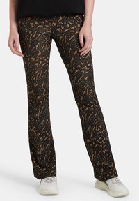 Rozšířené černé kalhoty s hnědým abstraktním vzorem, vyrobené z texturovaného materiálu. Mají vysoký pas a úzký střih přes stehna.