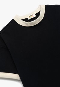 Czarny bawełniany t-shirt z kremowym ściągaczem przy okrągłym dekolcie i pasującymi mankietami. Metka nosi napis "Koton KIDS". Miękka tekstura.
