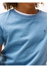 Niebieska bawełniana koszulka z krótkim rękawem i ściągaczem przy okrągłym dekolcie. Posiada małe logo w kolorze czerwonym, białym i niebieskim na klatce piersiowej. Miękka w dotyku.