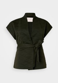 Patalynės apklotų viršus tamsiai žalias su trumpomis rankovėmis, rišamu dirželiu ir giliu V formos iškirpimu. Pasižymi deimantų raštu ir minkšta tekstūra.