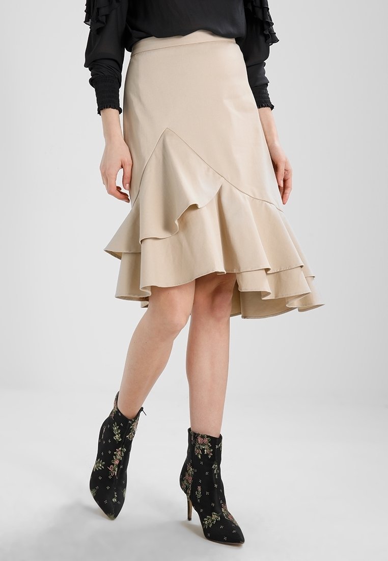 Beige flared skirt with layered ruffles and asymmetric hem. Worn with black ankle boots with floral patterns and stiletto heels.