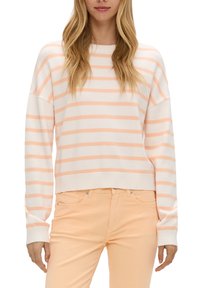 Leichter Strickpullover mit horizontalen Pfirsich- und weißen Streifen, lockerer Schnitt, runder Ausschnitt und gerippte Bündchen. Getragen mit pfirsichfarbenen Jeans.