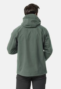 Giacca softshell verde con cappuccio, caratterizzata da un design slanciato, texture morbida e polsini elastici. Senza hardware visibile o loghi.