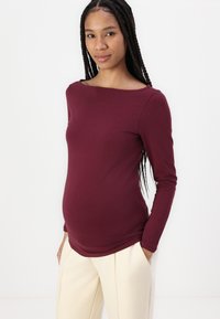 Bordo ilgomis rankovėmis marškinėliai su laivo iškirpte, pagaminti iš minkštos medžiagos. Sukurta patogiam prigludimui, akcentuojančiam pilvo sričiai.
