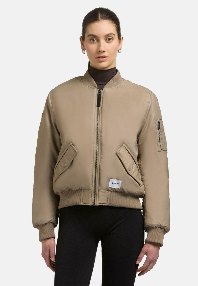 Beige Bomberjacke mit Reißverschluss, gerippten Bündchen und zwei Fronttaschen. Mit einer aufgesetzten Tasche am Ärmel und einem Logo-Label am Saum.