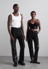 Black denim and faux leather pants with glossy accents. Pairing with a white tank top and a black sequined crop top. Simple, modern silhouettes.