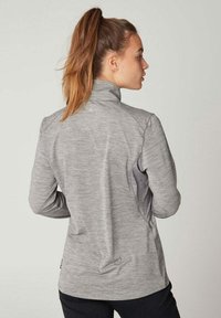 Graue, langärmlige Jacke mit hohem Kragen, strukturiertem Stoff und kontrastierenden grauen Seitenpanelen; taillierte Passform mit einer Naht im Rücken.