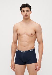 Caleçons boxers en coton bleu marine avec une ceinture blanche contrastante portant le logo "BOSS". Fabriqués en matériau doux pour le confort, au design ajusté.