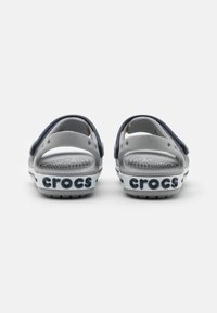 Grå og marineblå Crocs sandaler med åbne hæle, justerbare stropper og logo på hvid sål; teksturering på indersiden og letvægtsdesign.