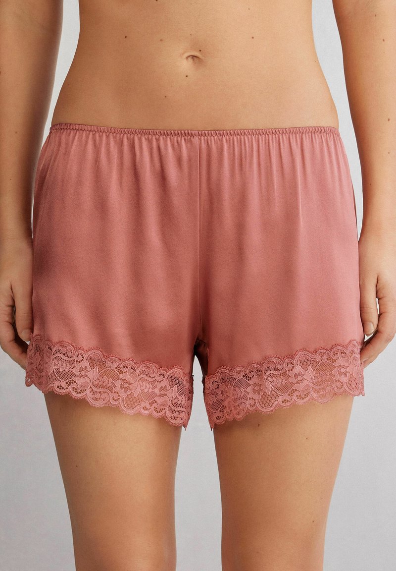 Rosaröda shorts i mjukt tyg med en scallopad spetsdetalj vid fållen. Elastisk midja för komfort och passform.