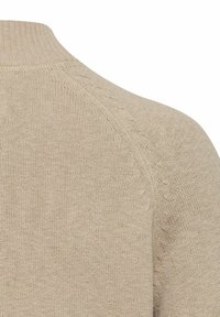 Beige strikket sweater med høj hals, raglanærmer og et tekstureret mønster nær sømmene. Blødt, let materiale.